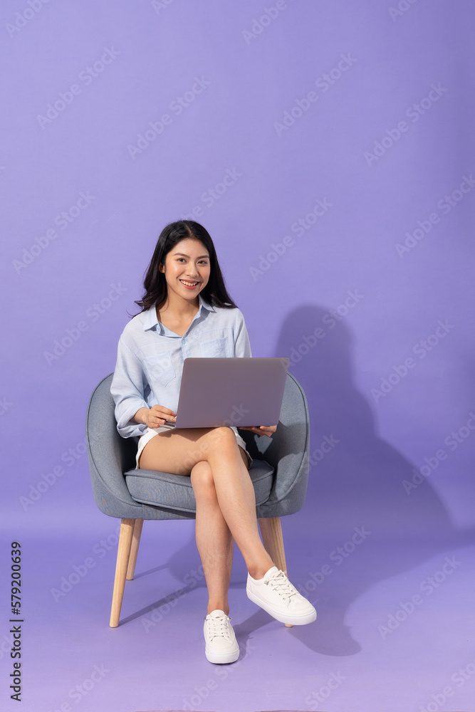 image of girl sitting on sofa isolated on purple background image of girl sitting on sofa isolated on purple background