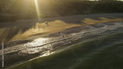 drone flight over Playa Grande Beach in Uruguay where Kids play in the waves at sunset photo
