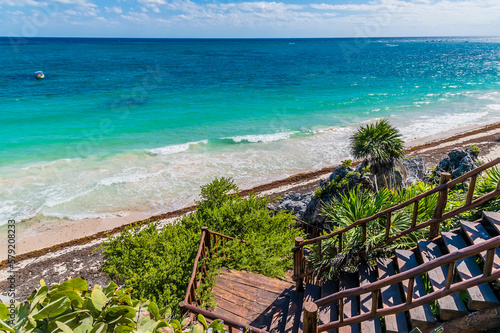 A view from the cliffs down to the beach at the Mayan settlement of Tulum, Mexico on a sunny day © Nicola