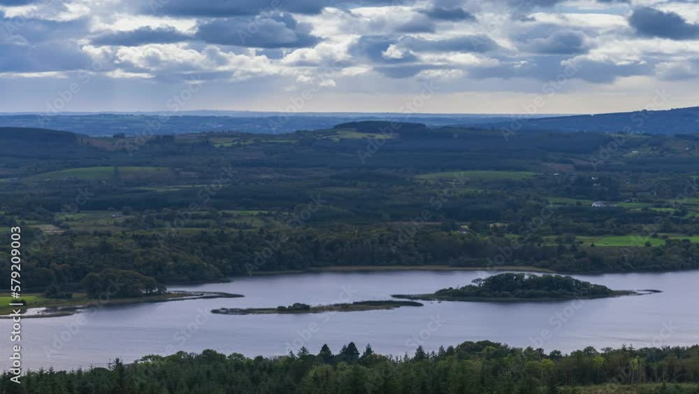 Time lapse of rural farming landscape with lake, forest and hills during a cloudy day viewed from above Lough Meelagh in county Roscommon in Ireland. Time lapse of rural farming landscape with lake, forest and hills during a cloudy day viewed from above Lough Meelagh in county Roscommon in Ireland.