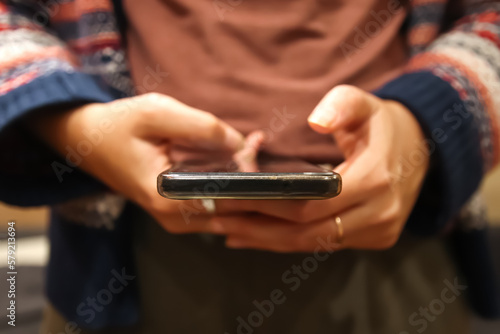 Closeup scrolling phone. Defocus female hand holding black phone. Close up of a woman using mobile smartphone. Millennial style. Social media. Out of focus