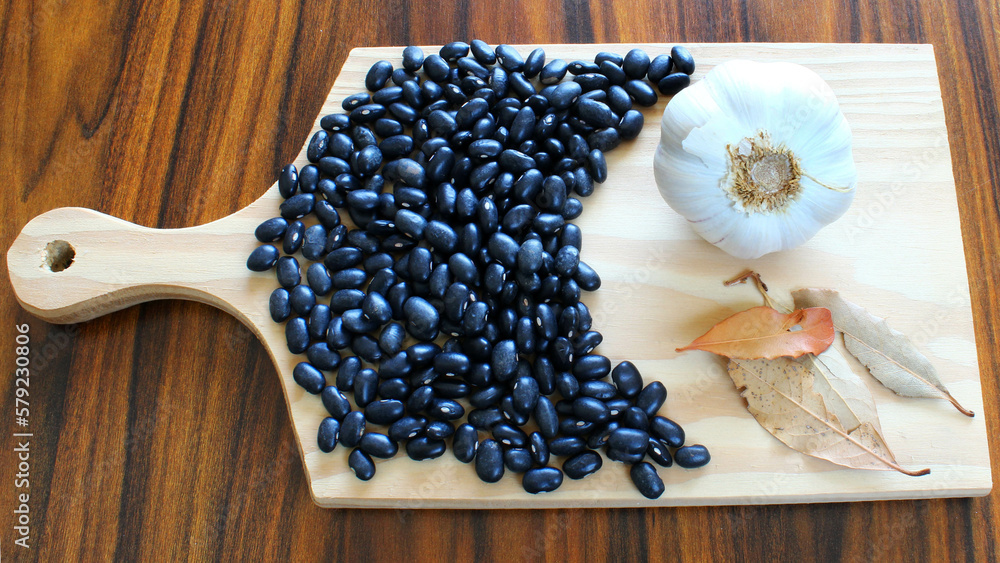 Black beans with brazilian seasonings. Garlic and bay leaves on the cutting board. Black beans with brazilian seasonings. Garlic and bay leaves on the cutting board.