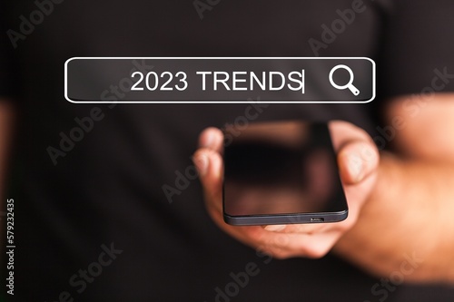 Businessman with smartphone and 2023 trends text
