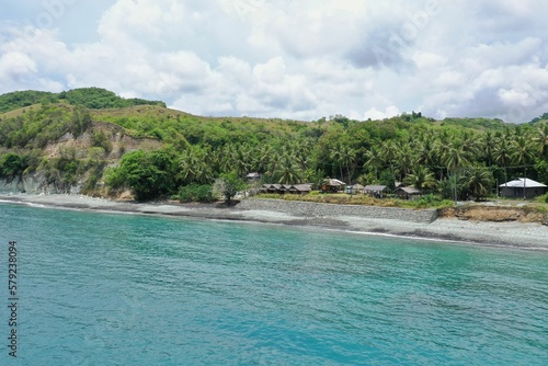 Panorama drone shot along the beach Pantai Batu Biru, the Blue Stone Beach, in the foreground the turquoise sea.