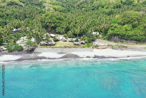 Panorama drone shot along the beach Pantai Batu Biru, the Blue Stone Beach, in the foreground the turquoise sea.
