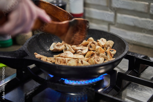 Chopped mushrooms are fried in frying pan on gas stove