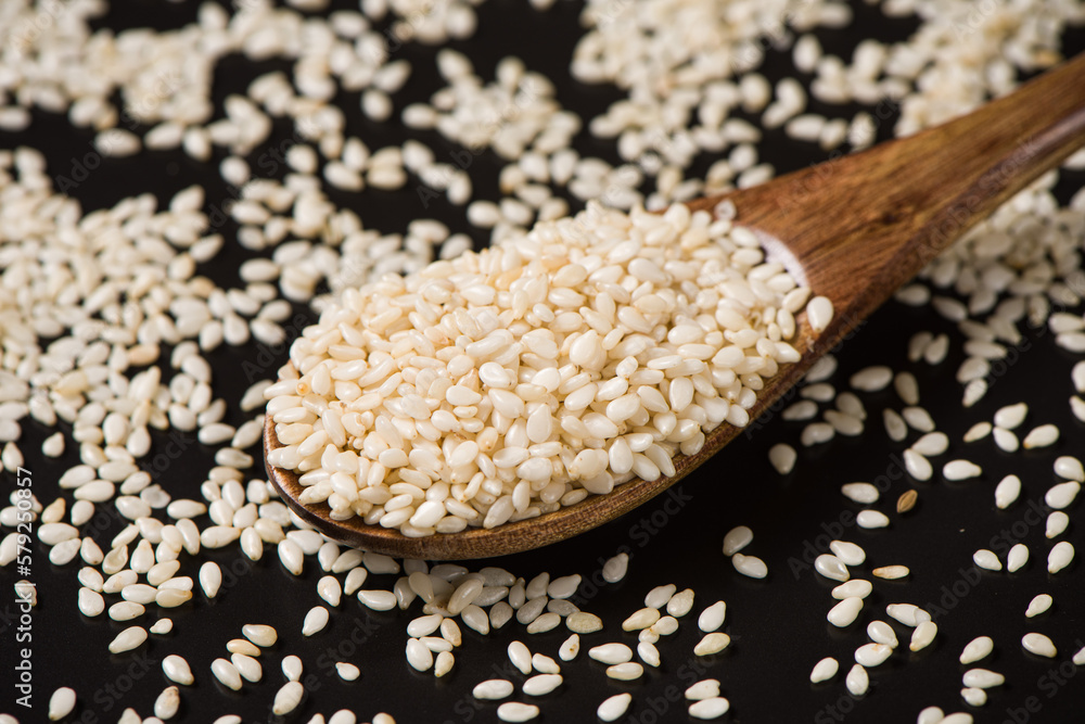 white sesame seeds in spoon on table. white sesame seeds in spoon on table.