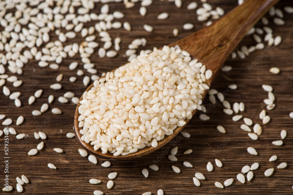 white sesame seeds in spoon on table. white sesame seeds in spoon on table.