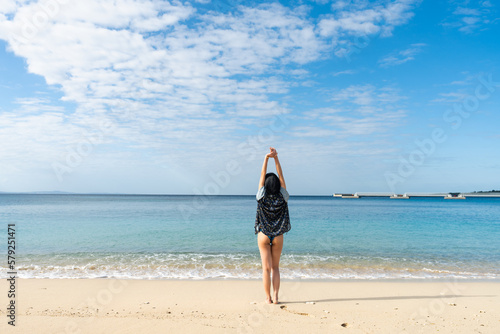 沖縄の海で水平線を眺めるビキニの女性