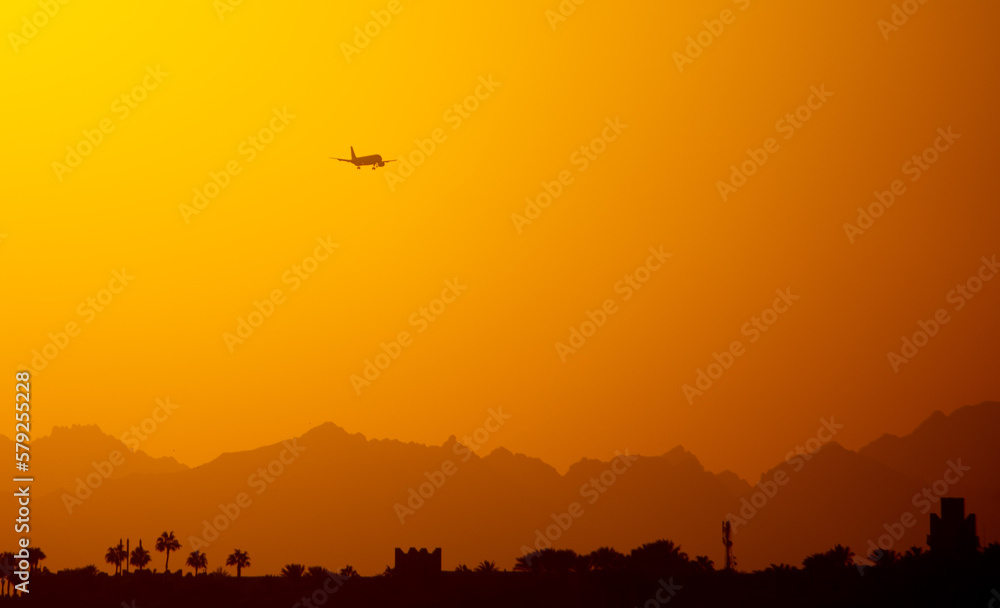 Obraz premium Silhouette of an airplane coming in for landing at sunset.