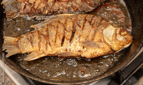 The fish is fried in oil in a frying pan.