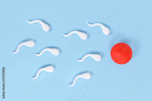 Photos Abstract sperm cells swimming towards egg cell on blue background