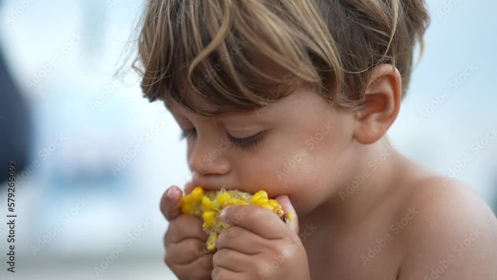 Kid eats corn snack outdoors. Child eating summer food. Healthy snacking Kid eats corn snack outdoors. Child eating summer food. Healthy snacking