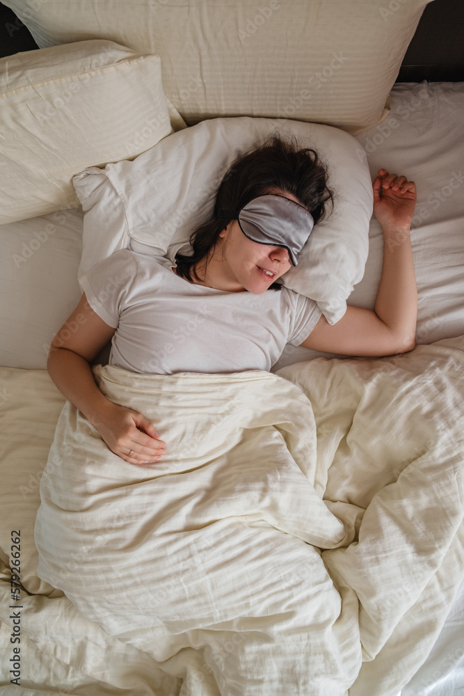 Top view of smiling woman waking up in white sheets Top view of smiling woman waking up in white sheets