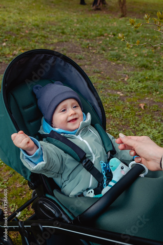 Smiling baby child in a stroller in the spring park