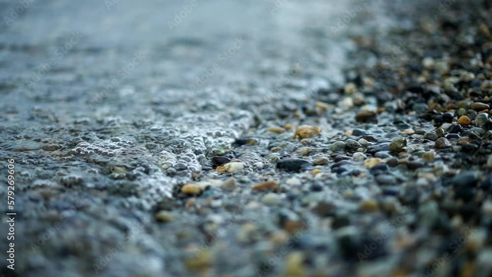 Lake sea shore with gravel rocks small waves crashing in super slow motion 240 fps Lake sea shore with gravel rocks small waves crashing in super slow motion 240 fps