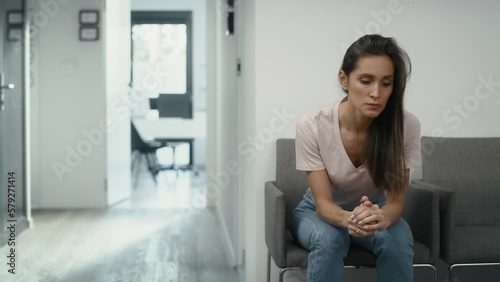Wide shot of stressed caucasian woman sitting in clinic waiting room and squeezing a stress ball. Shot with RED helium camera in 8K.