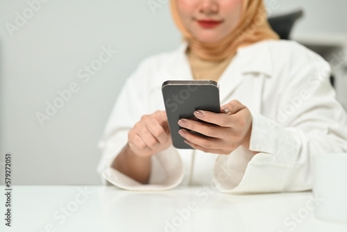 Millennial Asian muslim woman using mobile phone chatting online or communicating in social media