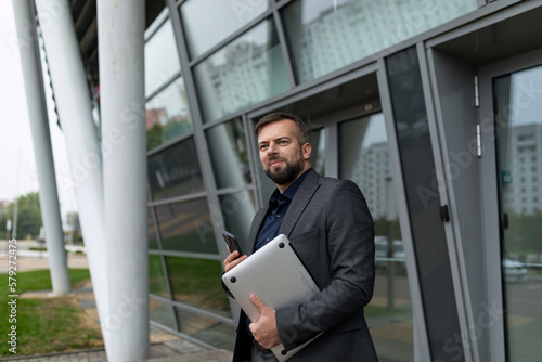 Wallpaper Mural satisfied freelancer man with a laptop in his hands against the backdrop of a business center Torontodigital.ca