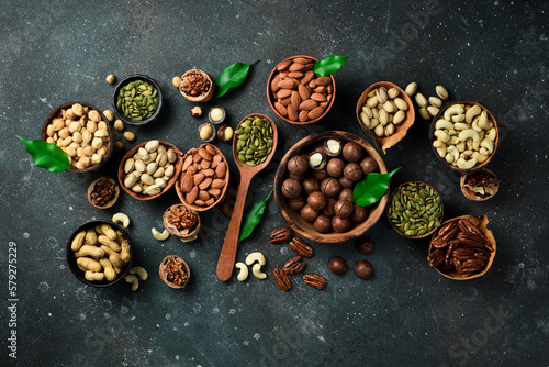 Nuts mix in a wooden plate. Top view. On a dark background.