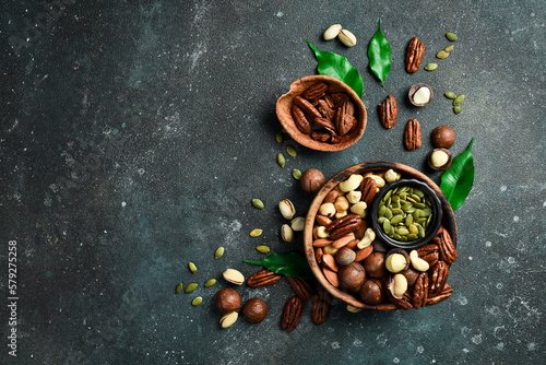 Various Nuts in wooden bowls. Top view. On a dark background.