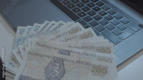 Person lying zloty banknotes hand fan on digital laptop,close up shot photo