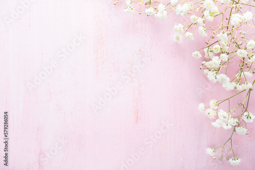 Tiny white flowers of Gypsophila on a light pink shabby wooden background. Top view with copy space. Flat lay. Selective focus
