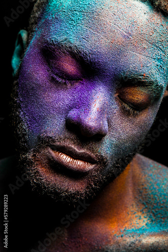 Black man in galaxy makeup with relaxed closed eyes on dark background in studio