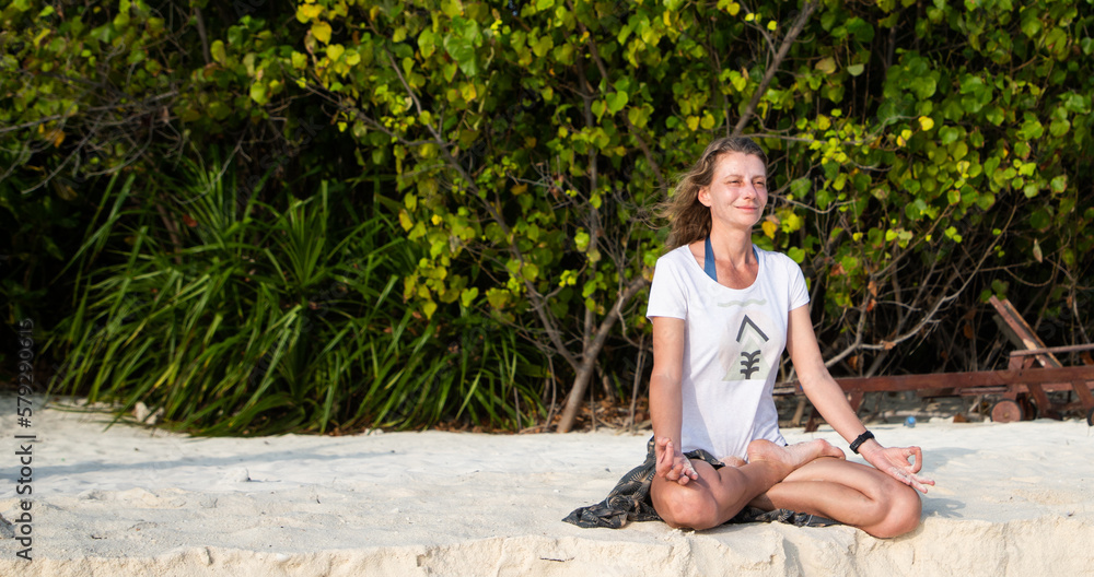 Naklejka premium woman doing yoga on tropical beach