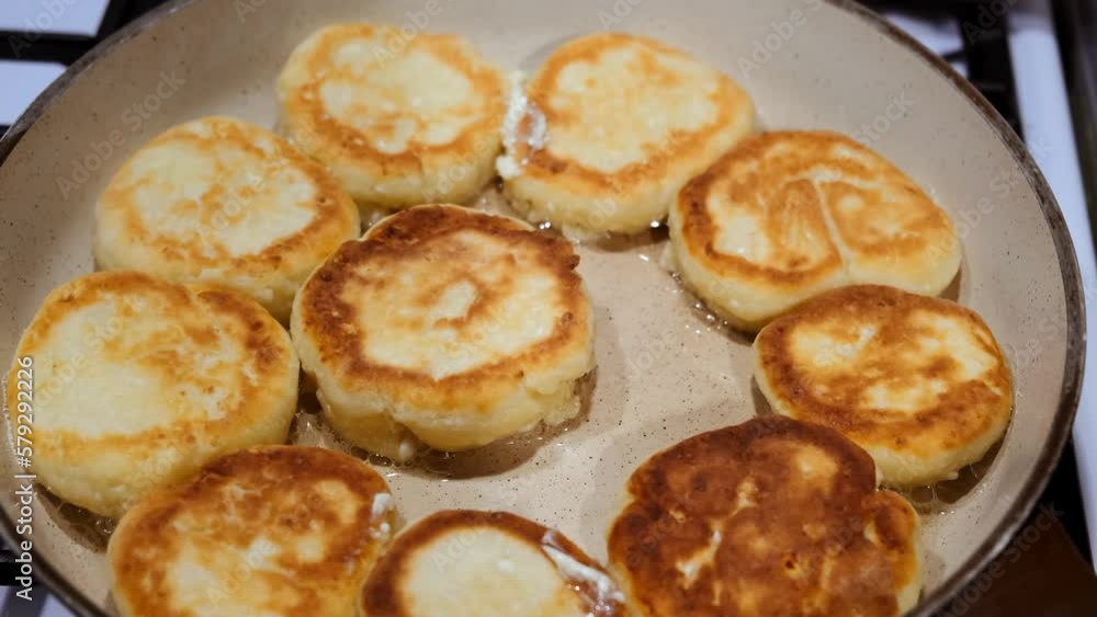 Cheesecakes are flying on a pan close-up. Cheese pancakes. Cooking process. Tasty breakfast. Food for children. The dish of curd. Traditional Russian cuisine. Olive oil. Bubbles of hot sunflower oil. Cheesecakes are flying on a pan close-up. Cheese pancakes. Cooking process. Tasty breakfast. Food for children. The dish of curd. Traditional Russian cuisine. Olive oil. Bubbles of hot sunflower oil.
