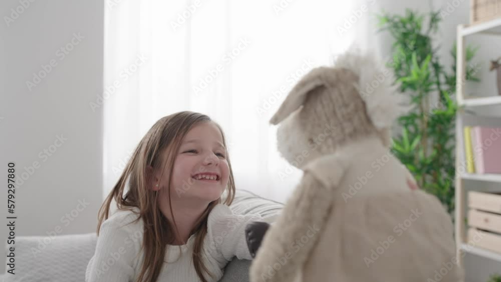 Little girl talking to soft toy on sofa. Imagination and innocence concept Little girl talking to soft toy on sofa. Imagination and innocence concept