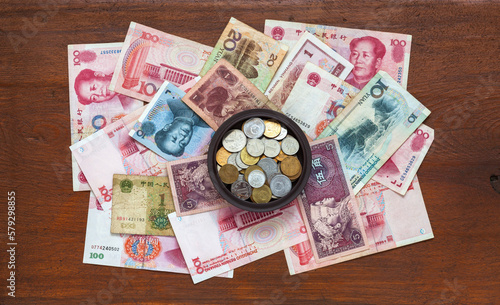 Flat lay of Chinese Yuan coins and heap of Yuan paper banknotes on a wooden background. Money and finance concept. Top view, close-up, mockup photo