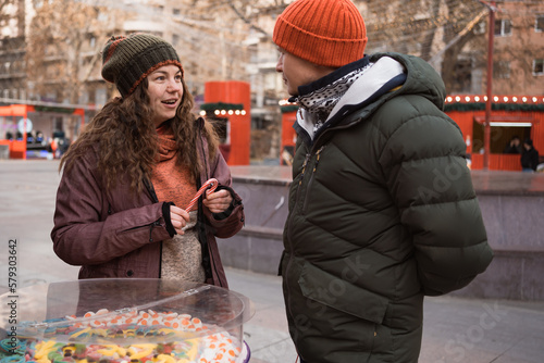 Adult couple in love bying christmas sweets at candy bar in street market at winter holidays photo