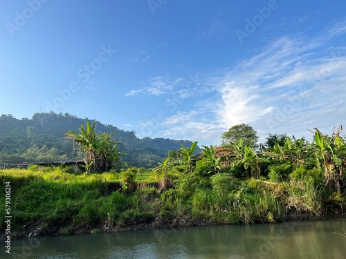 Beautiful landscape view of river  green forest with panoramic mountain and blue sky on the background.