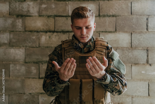 A Muslim soldier of the special forces prays to God by raising his hands and starts a prayer photo