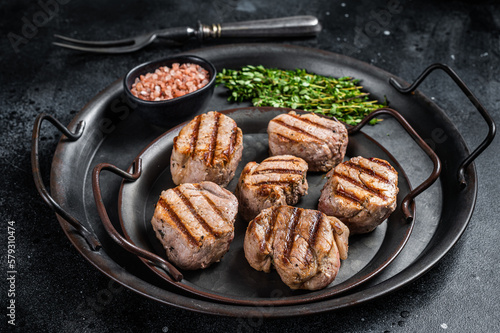 Roasted pork medallions steaks, tenderloin meat. Black background. Top view