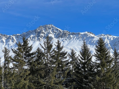 Beautiful sunlit and snow-capped alpine peaks above the Swiss tourist sports-recreational winter resorts of Valbella and Lenzerheide in the Swiss Alps - Canton of Grisons, Switzerland (Schweiz)