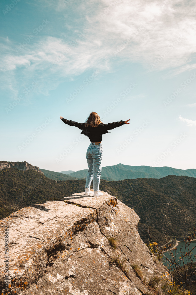 young woman celebrating the arrival at the top of a mountain, concept of victory, freedom, living