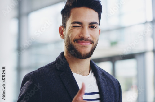 Ive got this. Cropped shot of a young businessman showing winking and showing thumbs up while walking through a modern office.
