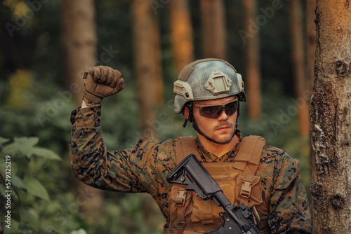 Modern warfare soldier officer is showing tactical hand signals to silently give orders and alers for squad team forest enviroment photo