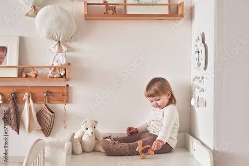 Baby in knitted clothes in children room. Nursery interior