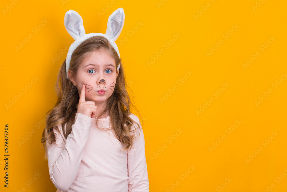 Funny girl with Easter bunny ears on yellow background with copy-space.