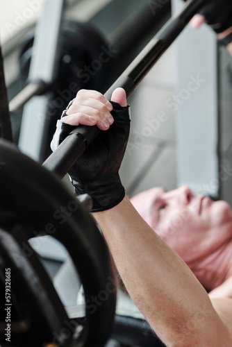 Determined mature man doing bench press exercise in gym