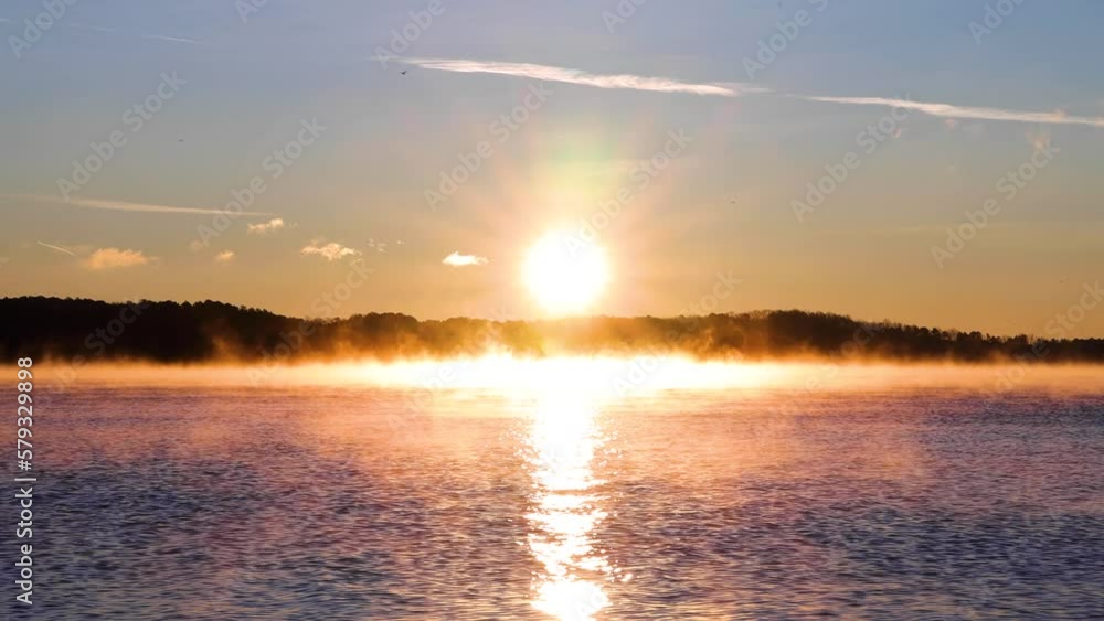 4k medium close up Sunrise over a lake with Mountain in the background, sun-ray sprinkling through water, blue and orange sky, Fog on Water 4k medium close up Sunrise over a lake with Mountain in the background, sun-ray sprinkling through water, blue and orange sky, Fog on Water