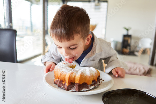 Little boy licks the icing sugar from the marble cake
