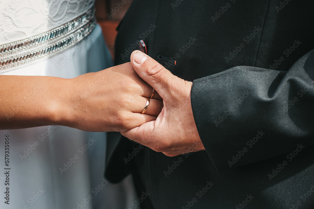 Close-up photo of the hands of the bride and groom, decorated with wedding rings. The beauty of their intertwined fingers. Rings on the hand of the bride and groom