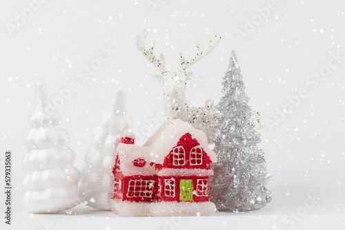 Christmas scene, miniature dacha village. Christmas little red houses, deer and snowy fir trees on a white background. Festive modern decorations.