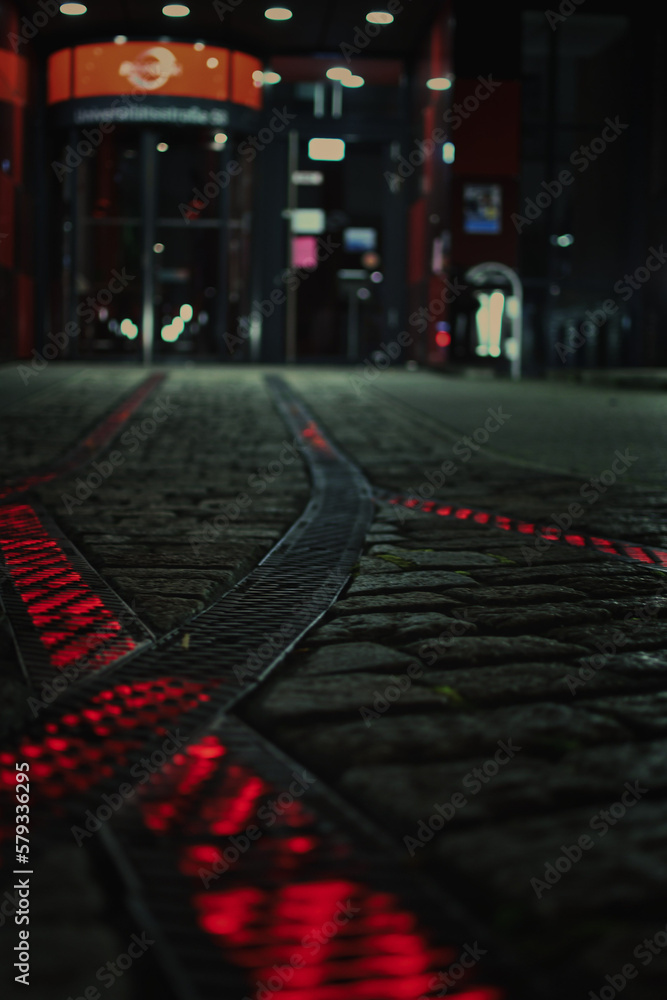 Red luminous rails on the forecourt in front of a headquarter in Bochum, Germany. - obrazy, fototapety, plakaty 