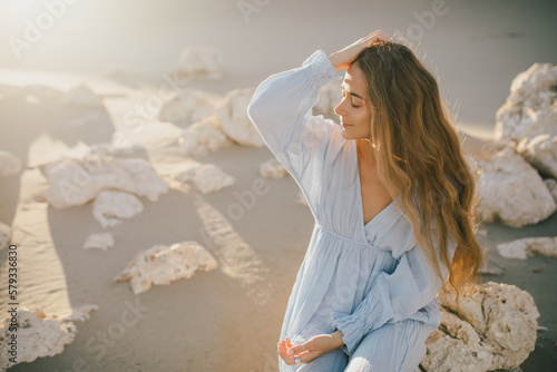 Fotografiet Woman with long hair in a stylish dress poses in the desert sands