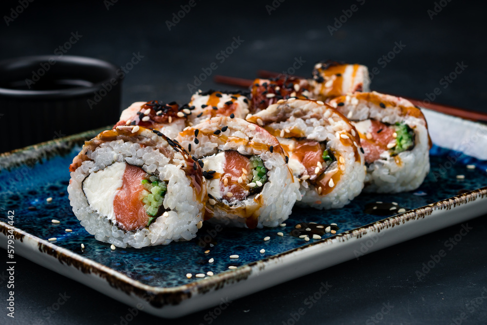 Sushi rolls with salmon, bacon, cream cheese, cucumber, sesame and teriyaki sauce.